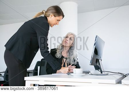 Project Manager Affixing Signature On Employees Report. Female Business Colleagues Sitting And Stand