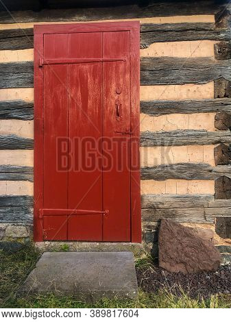 Red Wooden Door With Long, Old Style Hinges In An Early American Log Cabin On The Daniel Boone Homes
