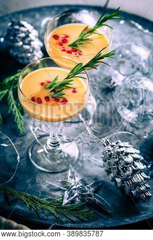 Traditional egg liqueur or eggnog with cinnamom, pomegranate and rosemary  with Christmas decoration
