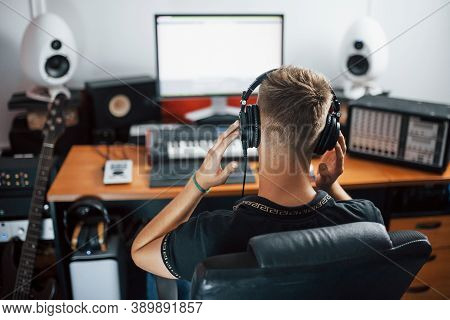 Sound Engineer In Headphones Working And Mixing Music Indoors In The Studio.