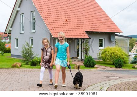 Dois jovens ou crianças - irmãs - caminhar com o cão