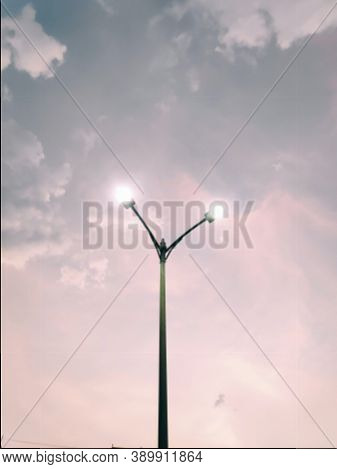 Lamp Post With Two Led's Lighten Up In Pink Sky In Background In Beautiful Evening
