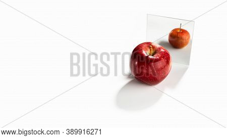 A Red Large Adult Apple On A White Background Looks In The Mirror And In The Reflection Sees Himself