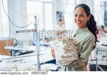 Woman Dressmaker Stands In The Factory With Cloth In Hands.