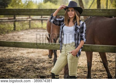American Woman On A Horse Farm. Portrait Of Girl In Cowboy Hat With A Horses. Hippotherapy At Nature