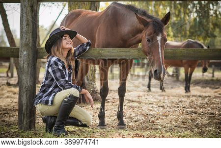 American Woman On A Horse Farm. Portrait Of Girl In Cowboy Hat With A Horses. Hippotherapy At Nature