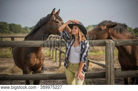 American Woman On A Horse Farm. Portrait Of Girl In Cowboy Hat With A Horses. Hippotherapy At Nature