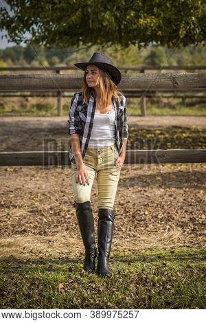 American Woman On A Horse Farm. Portrait Of Girl In Cowboy Hat With A Horses. Hippotherapy At Nature