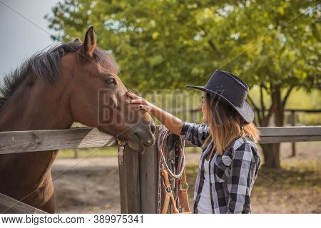 American Woman On A Horse Farm. Portrait Of Girl In Cowboy Hat With A Horses. Hippotherapy At Nature