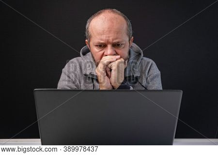 Man In Hoodie Working From Home Office, Worried Face Expression. Adult Bearded Man Sitting Behind Co