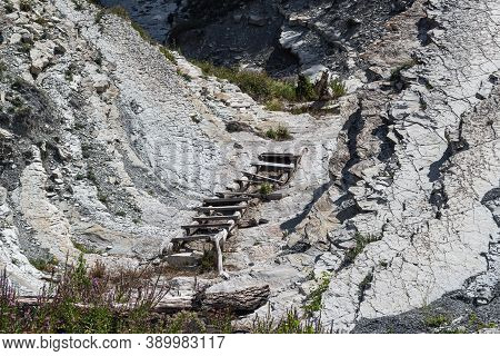 An Old Wooden Staircase And Massive White Rocks On A Wild Beach. The Path To The Camp Goes Through T