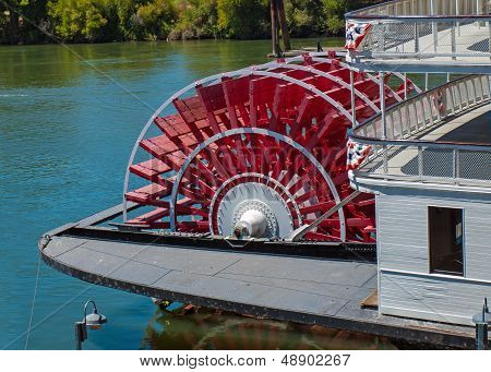 Red Riverboat Paddle Wheel In A River With Trees