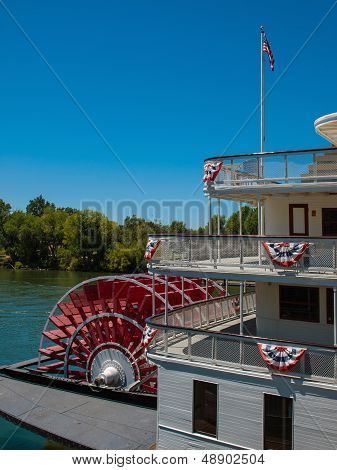 Red Riverboat Paddle Wheel In A River With Trees