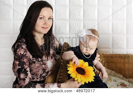 Happy Mother Holds Sunflower And Shows It To Her Little Daughter.