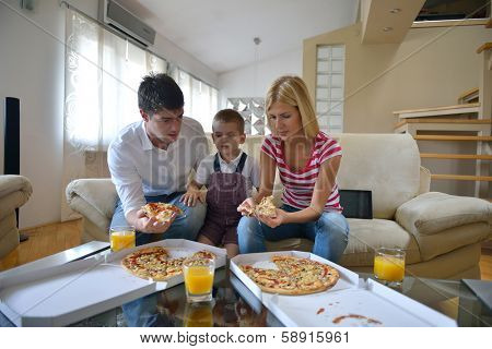 happy young family eating tasty pizza with cheesa and dring healthy and fresh orange juice