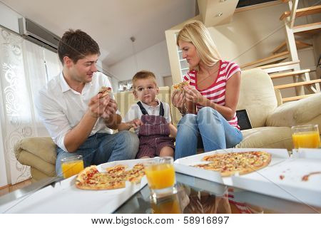 happy young family eating tasty pizza with cheesa and dring healthy and fresh orange juice