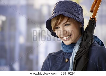 Portrait of attractive young woman with umbrella, smiling.