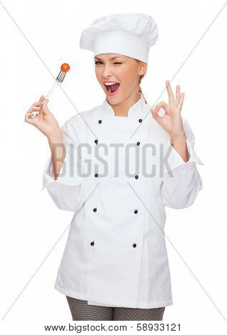 cooking and food concept - smiling female chef, cook or baker with fork and tomato showing ok sign