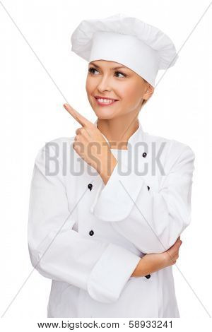 cooking, advertisement and food concept - smiling female chef, cook or baker pointing finger to something