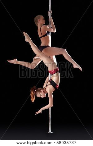 Two athletic young girls dancing on pilon