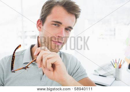 Portrait of a casual male photo editor smiling in a bright office