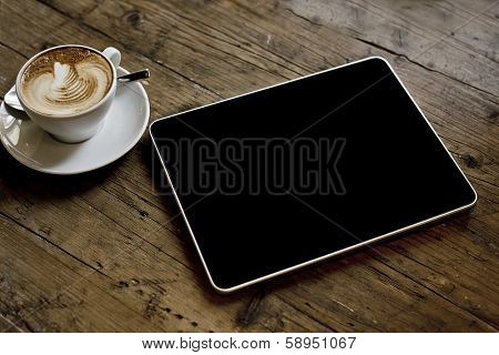 blank tablet computer on a wooden background next to a cup of coffee