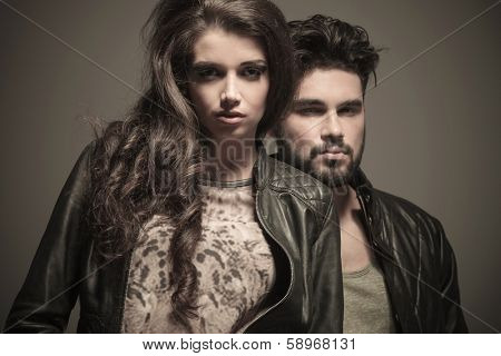 dramatic fashion couple in studio, man standing behind woman, looking at the camera