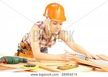 Blond female carpenter measuring a batten isolated on white background