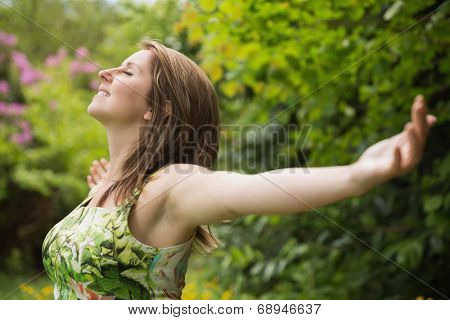 Close-up of young woman with arms outstretched in field