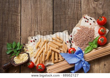 Pasta, Tomatoes, Basil And Parsley On Wooden Background