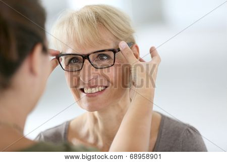 Senior woman trying new eyeglasses in optical store