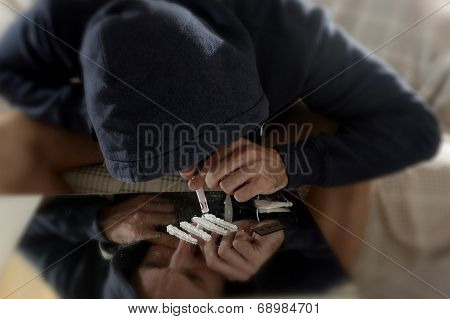 Young Drug Addict Man On Hood Alone Sniffing And Snorting Cocaine Lines With Rolled Banknote On Mirr