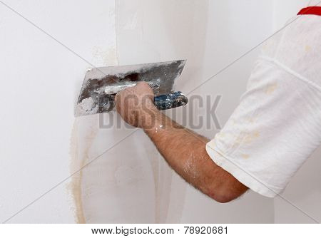 Worker Repairing Plaster To Wall