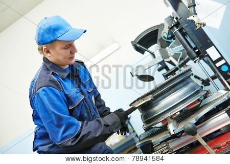 Auto repairman cleaning automobile car wheel rim at tyre fitting machine during tire replacing