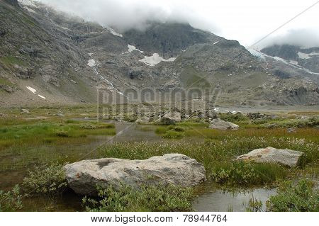 Rocks In Valley Nearby Glacier In Alps In Switzerland