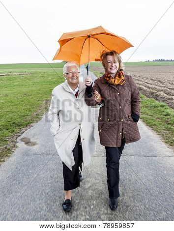 Women In Rain Under An Umbrella In Rural Landscape