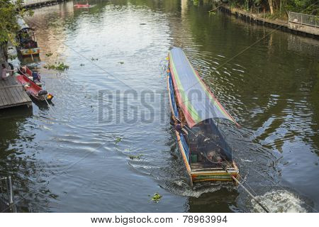 BANGKOK, THAILAND - DEC 19, 2014: A long-tail boat carrying local people passing on the Chao Praya River. Long-tail boats are a cheap (15 baht/ $0,5) form of river transport in the Thai capital.