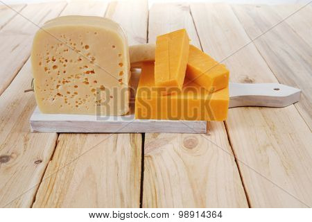 various types of fresh raw aged delicatessen cheese on white plate over light wooden table cheddar edam swiss