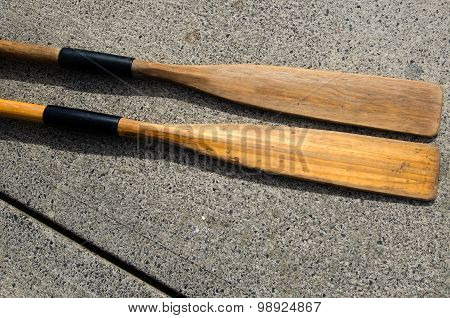 Two old wooden weathered paddles (oars) on concerete.