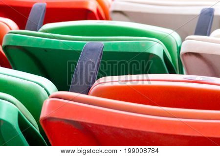 Folding plastic chairs in green, white, red, orange at an event. These are common in concert halls, stadiums, race tracks and where large crowds are seated
