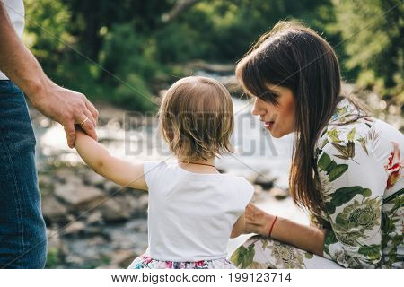 happy family play with daughter near the river in mountains, old bridge on backgeound