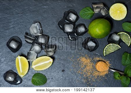 Refreshing mint cocktail mojito ingredirnts, cold drink or beverage with ice on black background, top view