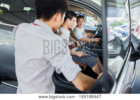 Dongguan, Guangdong, China - August 7, 2017: Car salesperson talking with prospective Chinese brand automobile buyers at Dongguan car exhibition