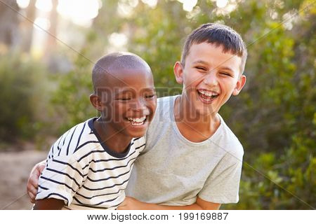 Portrait of two boys embracing and laughing hard outdoors