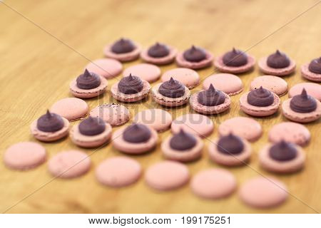 cooking, confectionery and baking concept - macarons with buttercream filling on table at bakery