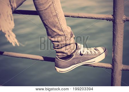 Blue Trendy Sneaker On Girl Leg In Jean Over Green Sea Backgroundretro Effect