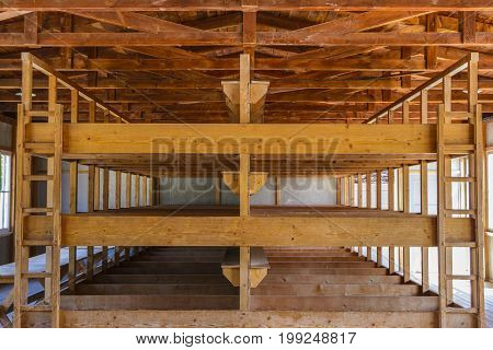 Dachau Concentration Camp Germany - July 30 2016: Inside sleeping quarters with wooden bunk beds from barrack room showing terrible prisoners living conditions from extermination camp.