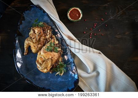Grilled chicken Tabaka with sauce on stone plate.