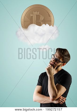 Handsome young european man thinking about bitcoins in clouds on blue background. Cryptocurrency concept