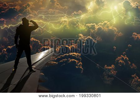 silhouette of man who looking the thunder lightnings over the clouds and storm on airplane wing Challenge business concept